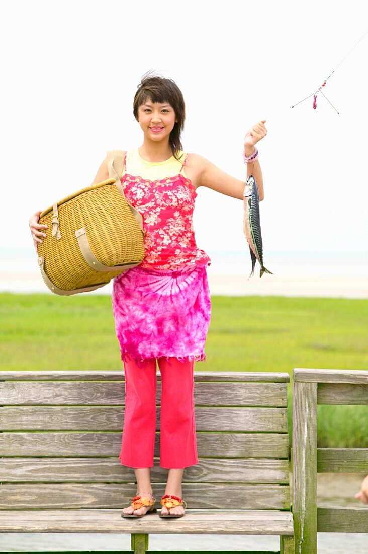 Frau hält frisch gefangenen Fisch und Korb