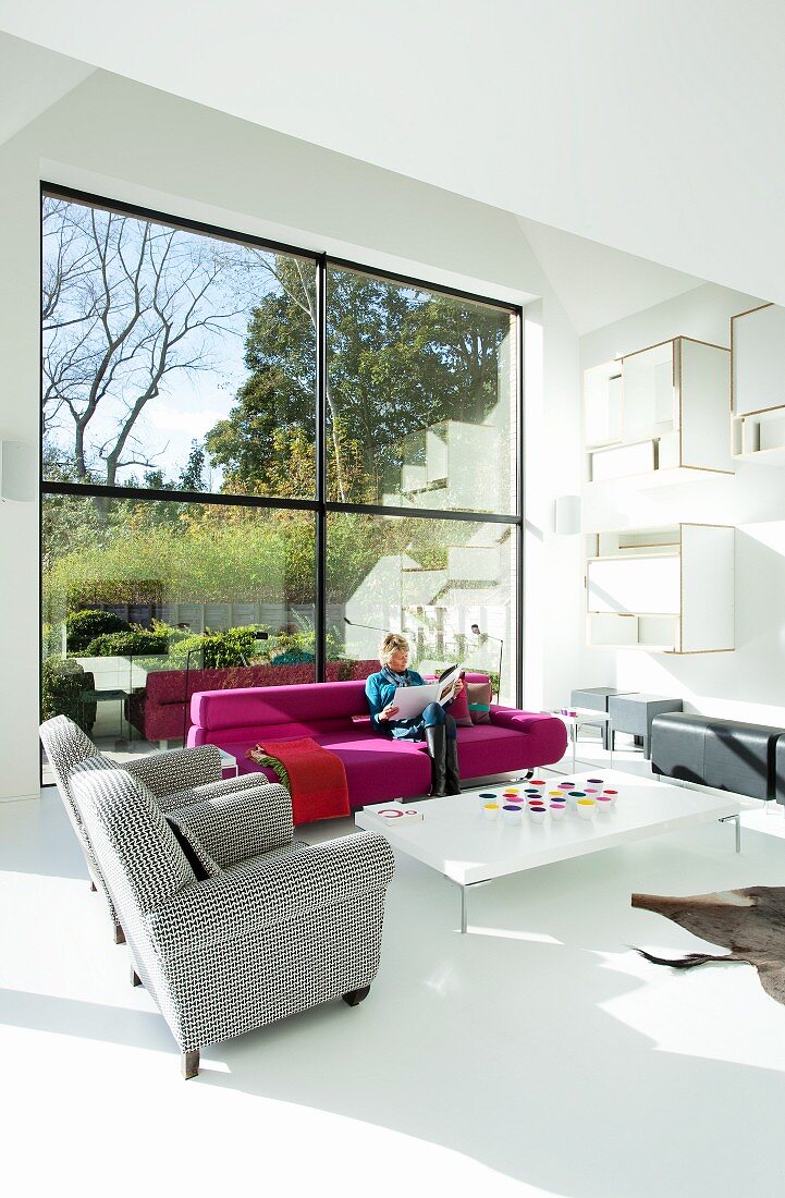 Designer lounge area with various upholstered furnishings in front of double-height panoramic window