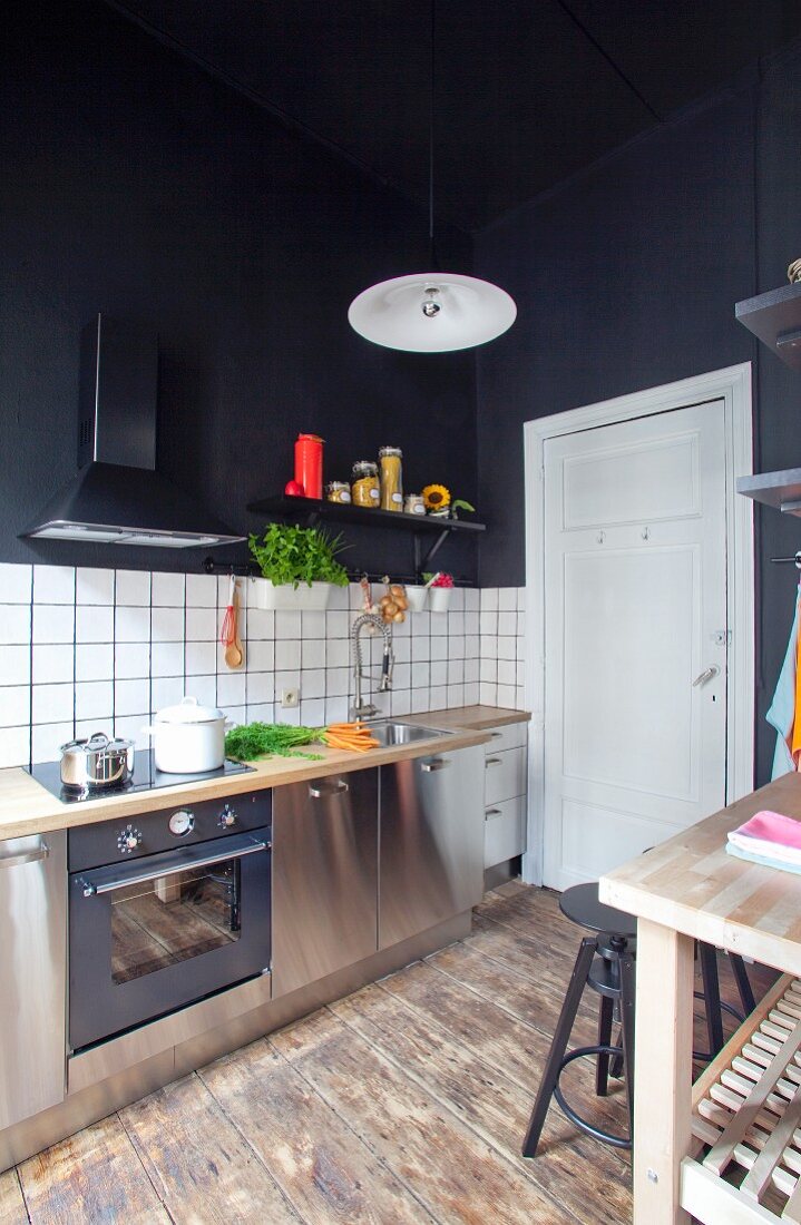 Kitchen counter with white, tiled splashback and black-painted walls and ceiling in renovated period apartment