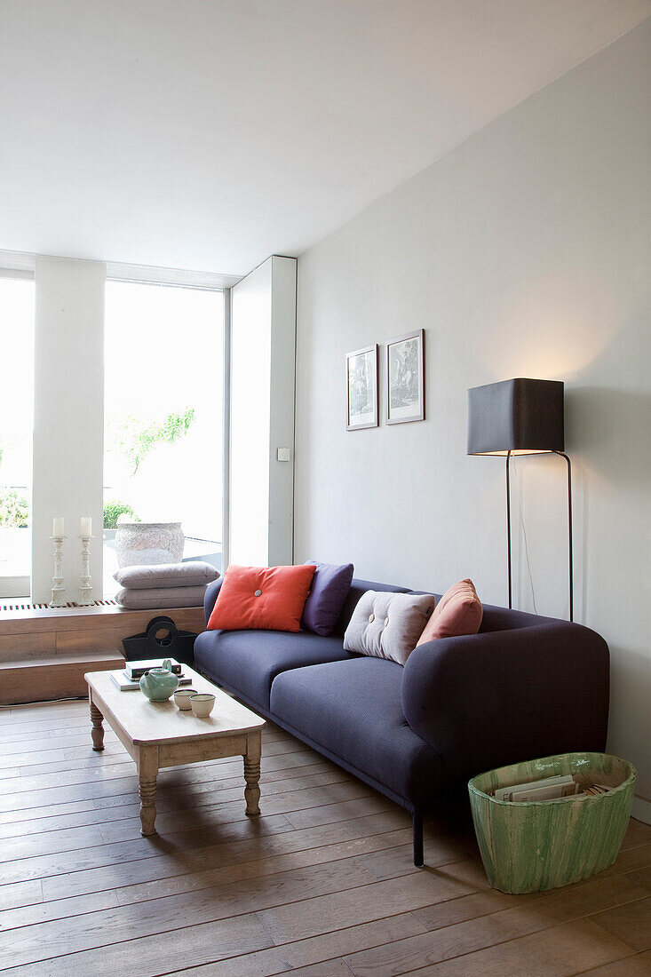 Dunkles Sofa und Couchtisch aus Holz in hellem Wohnzimmer mit Holzboden