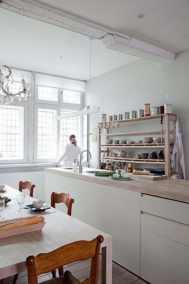 Bright dining area with rustic wooden table and open shelves in a kitchen