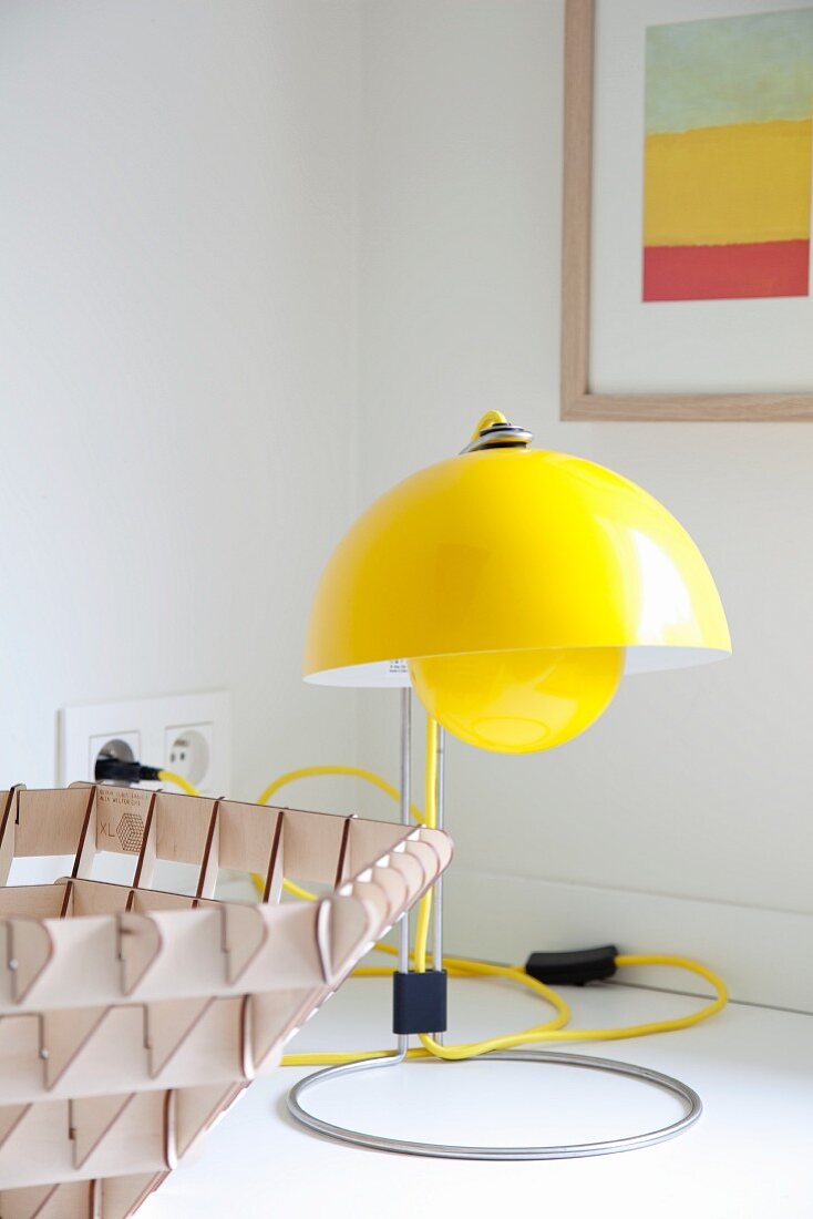 Gelbe Designer Tischleuchte im Retrolook mit gelbem Stromkabel auf weißer Unterlage
