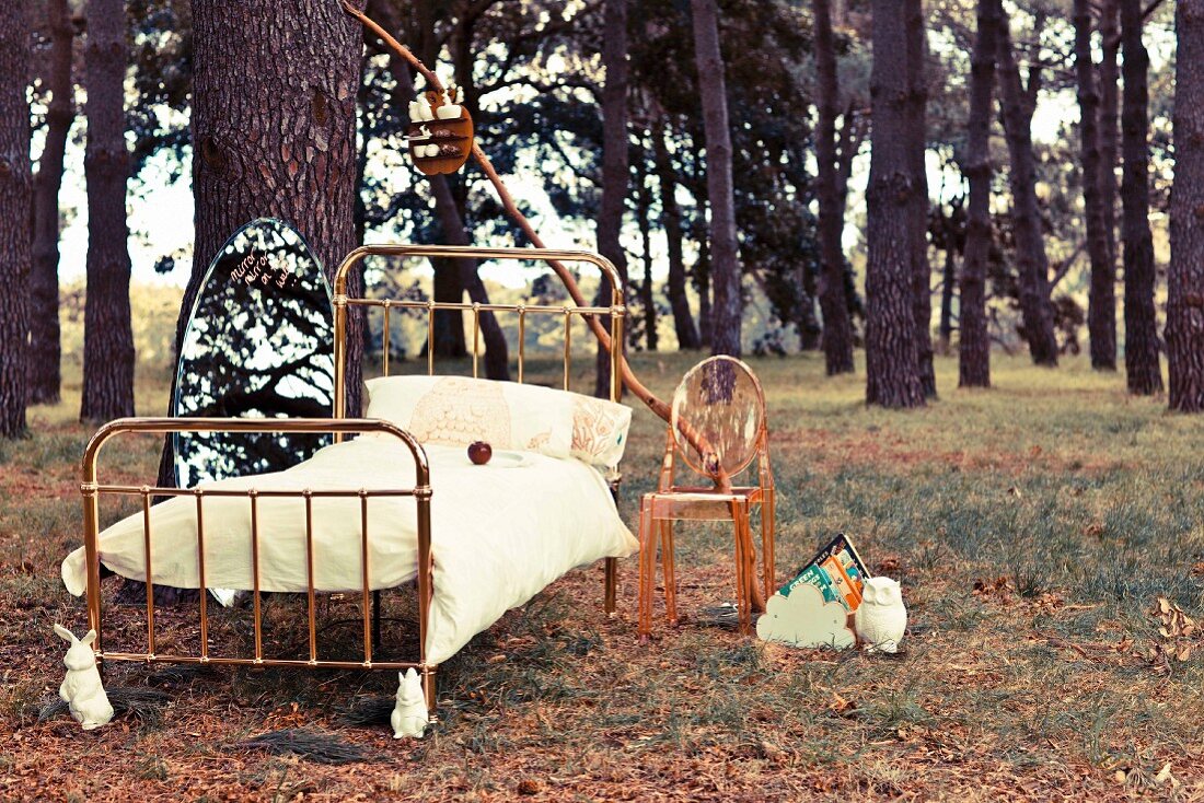 Fairytale: metal bed and a transparent chair in the forest