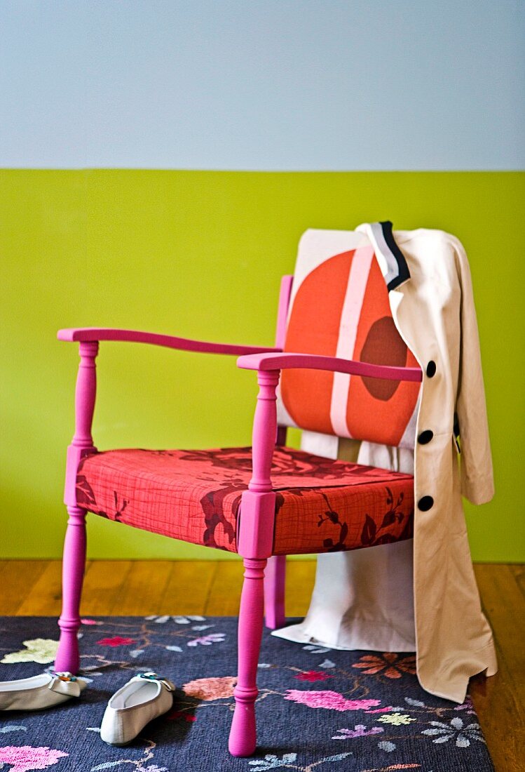Chair in various shades of red on a floral patterned rug in front of a colorful wall
