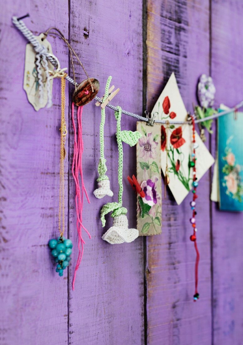 Crocheted flowers, beads and pictures of flowers pegged on cord