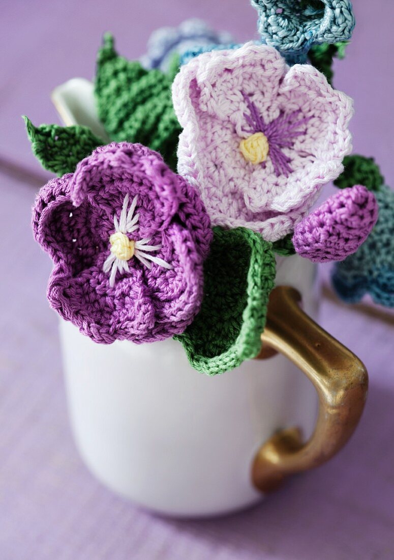 Purple crocheted flowers arranged in nostalgic milk jug