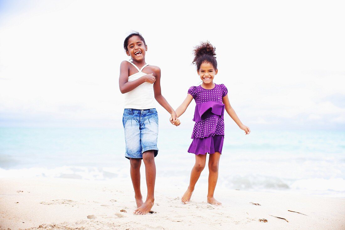 Zwei dunkelhäutige Mädchen stehen Hand in Hand am Strand