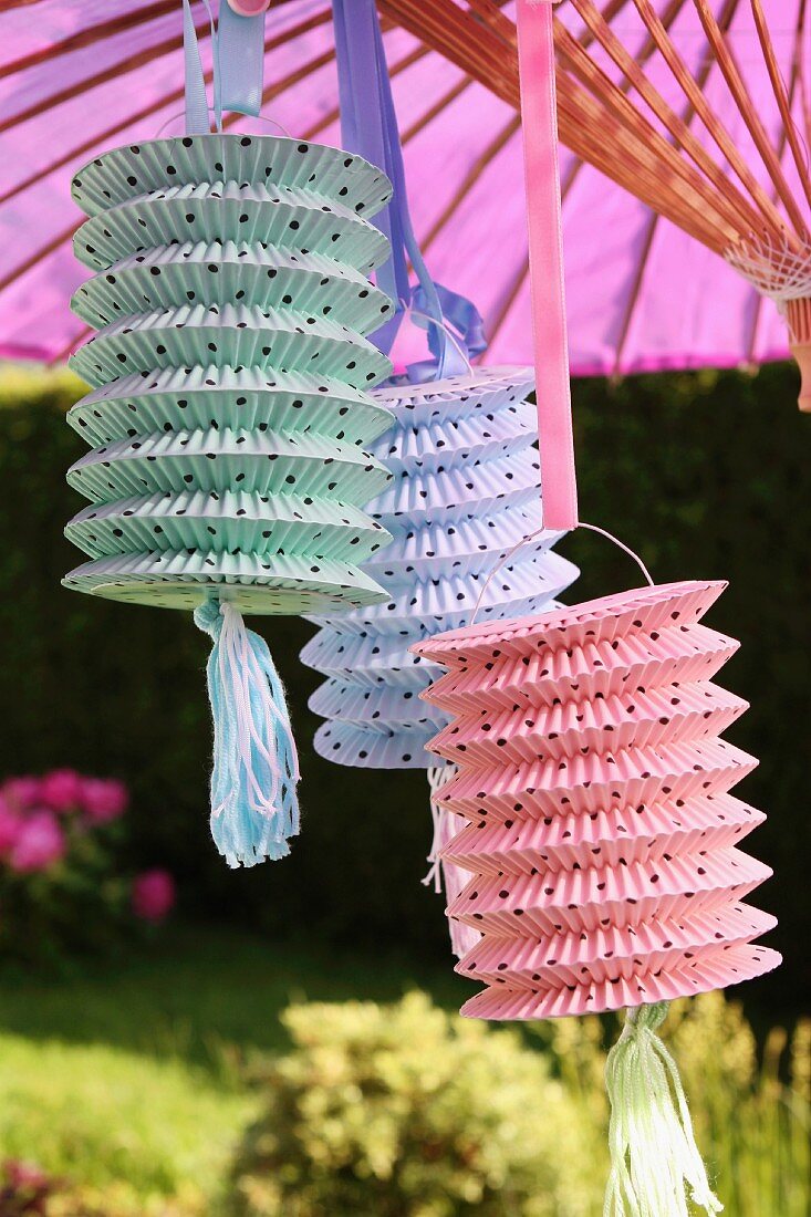 Verschiedenfarbige Lampions aus Papier am Sonnenschirm im Garten