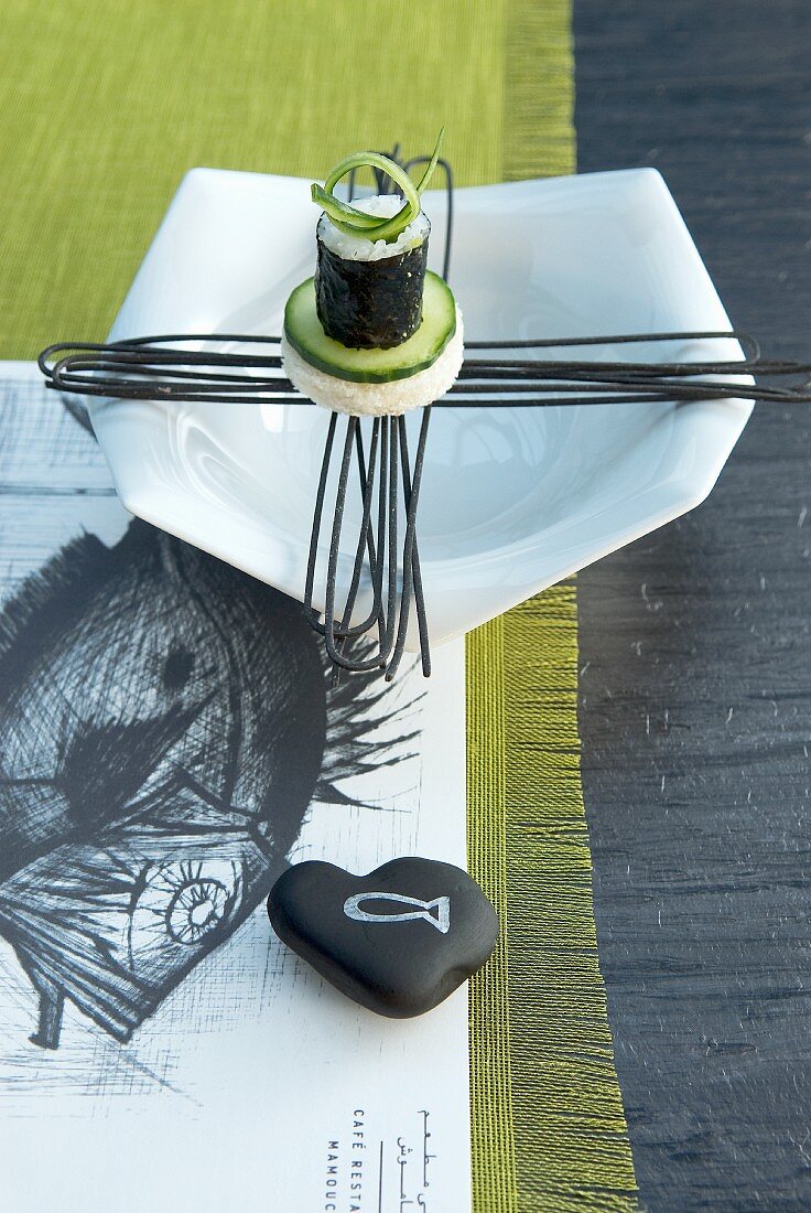 Designer-Teller mit Sushi auf Papierset mit Fischzeichnung und Tischläufer
