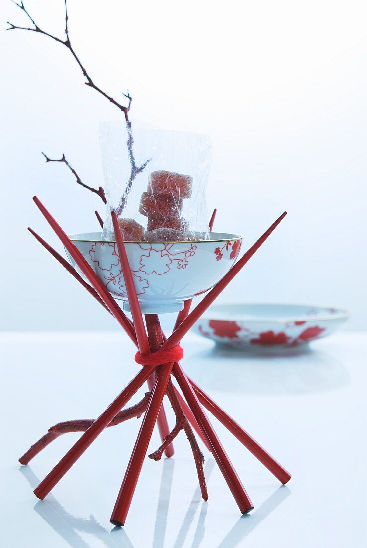 Asiatische Tischdeko: Gestell aus roten Essstäbchen darauf asiatische Schale