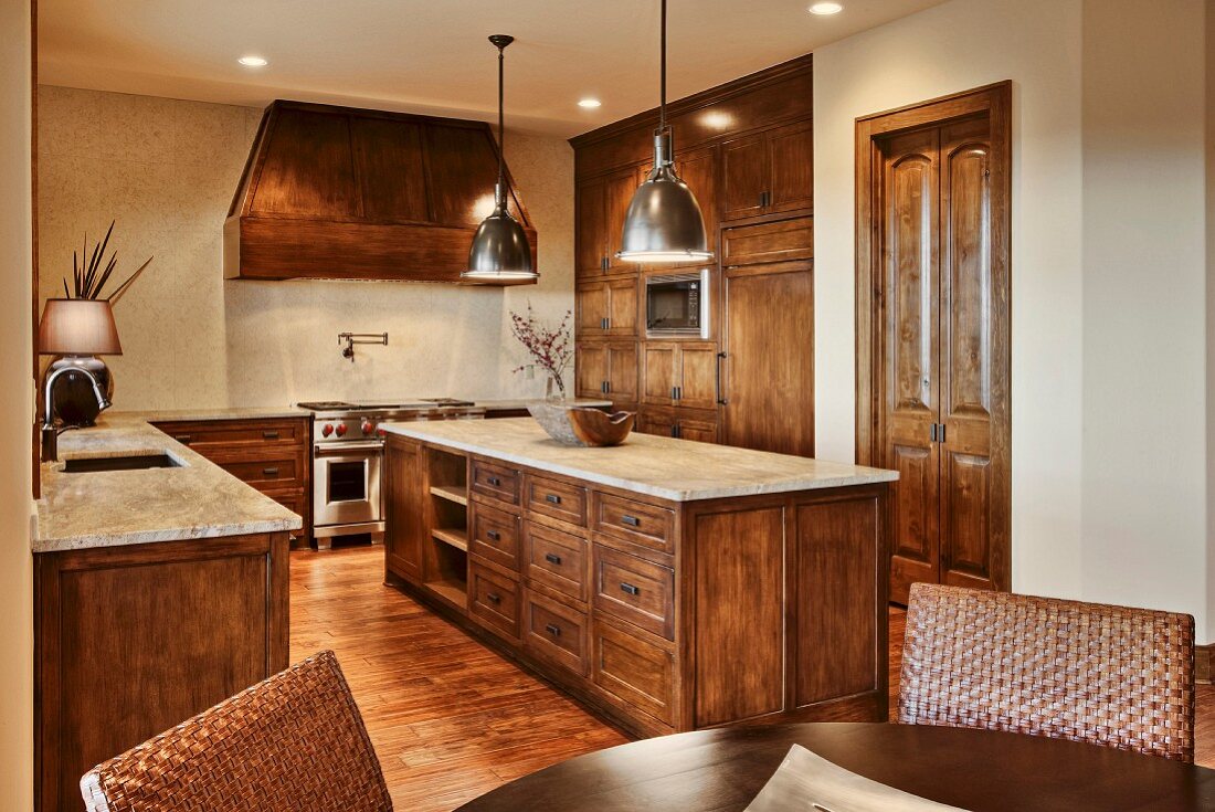Dining area in front of open-plan, rustic, country-house-style kitchen with freestanding, solid wooden central island