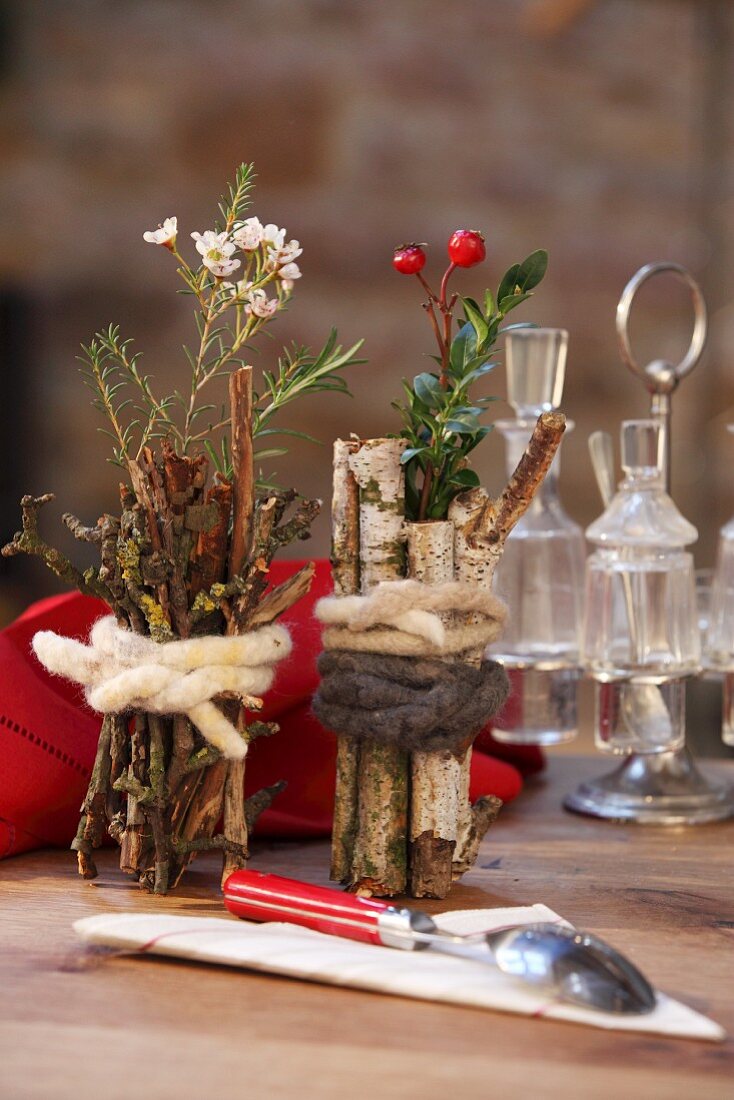 Small vases wrapped in birch branches twigs and tied with felting wool