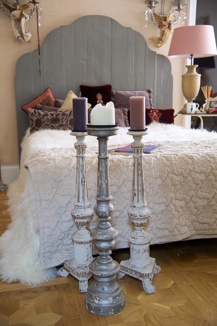 Boden Kerzenständer vor französischem Bett mit Holz Kopfteil neben Nachttischleuchte mit rosa Schirm