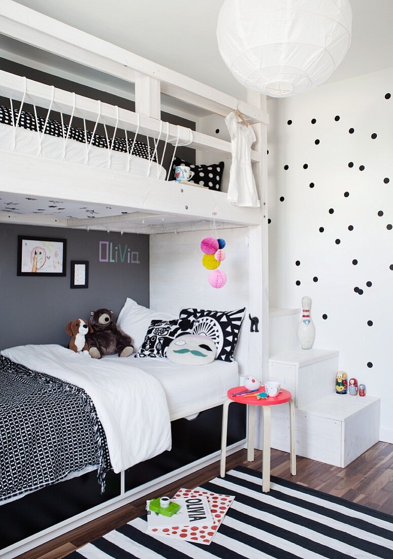 Schwarzweisse Bettwäsche auf Stockbett mit weißem Holzgestell und Streifenteppich in Kinderzimmer