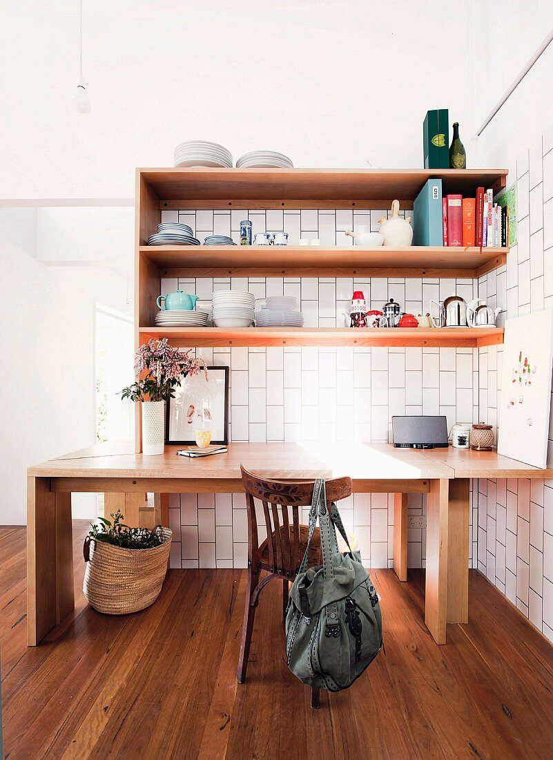 Holztisch unter Regalen mit Geschirr auf Holzboden