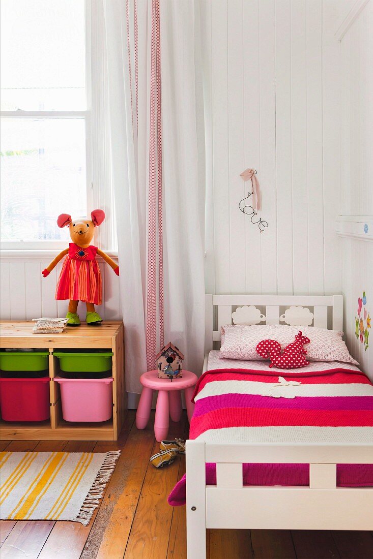 Bunte Möbel im Kinderzimmer mit Holzboden und Bretterwand