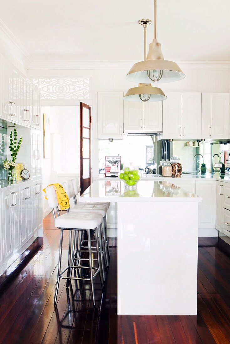 White. country-house-style fitted kitchen, bar stools and glossy wooden floor
