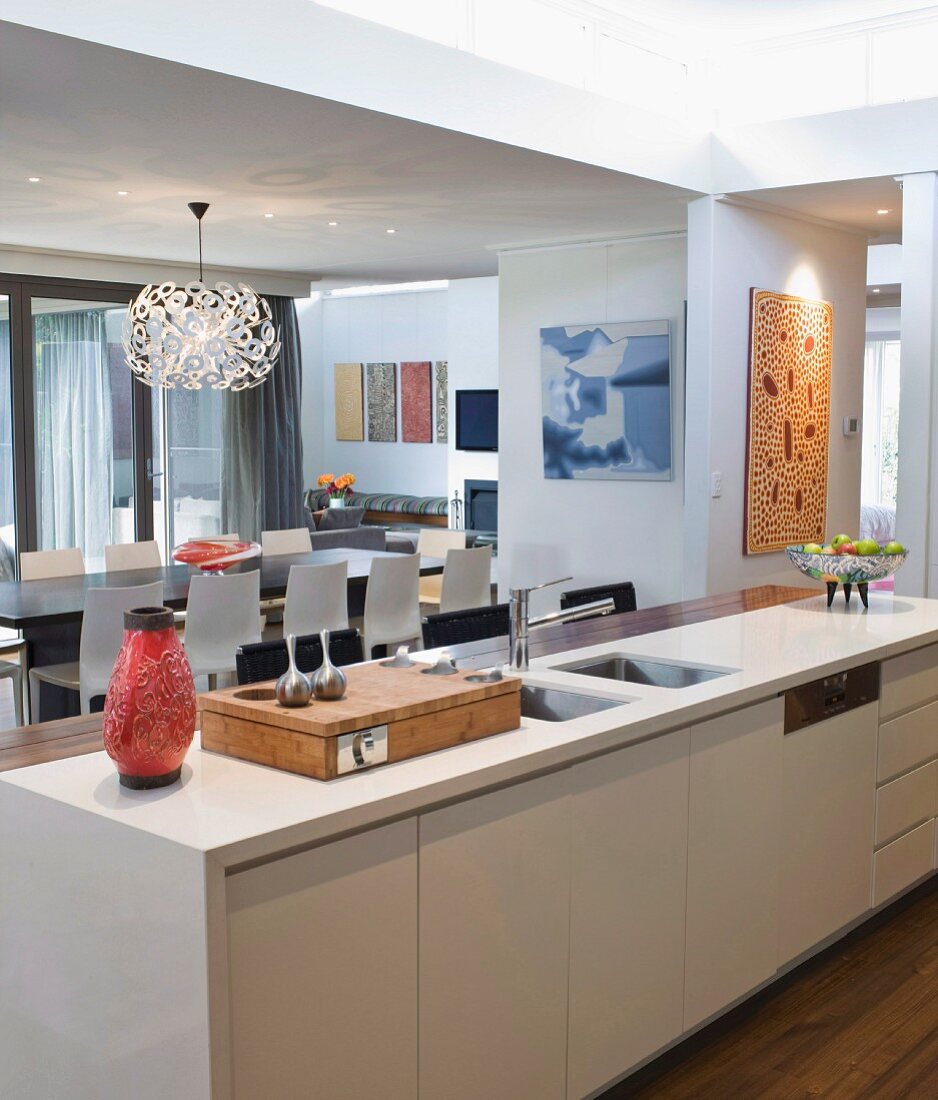 Blick von Küchentheke mit Dekoobjekten aus den 60er Jahren auf offenen Wohnraum mit Designerleuchte Dandelion über dem Esstisch