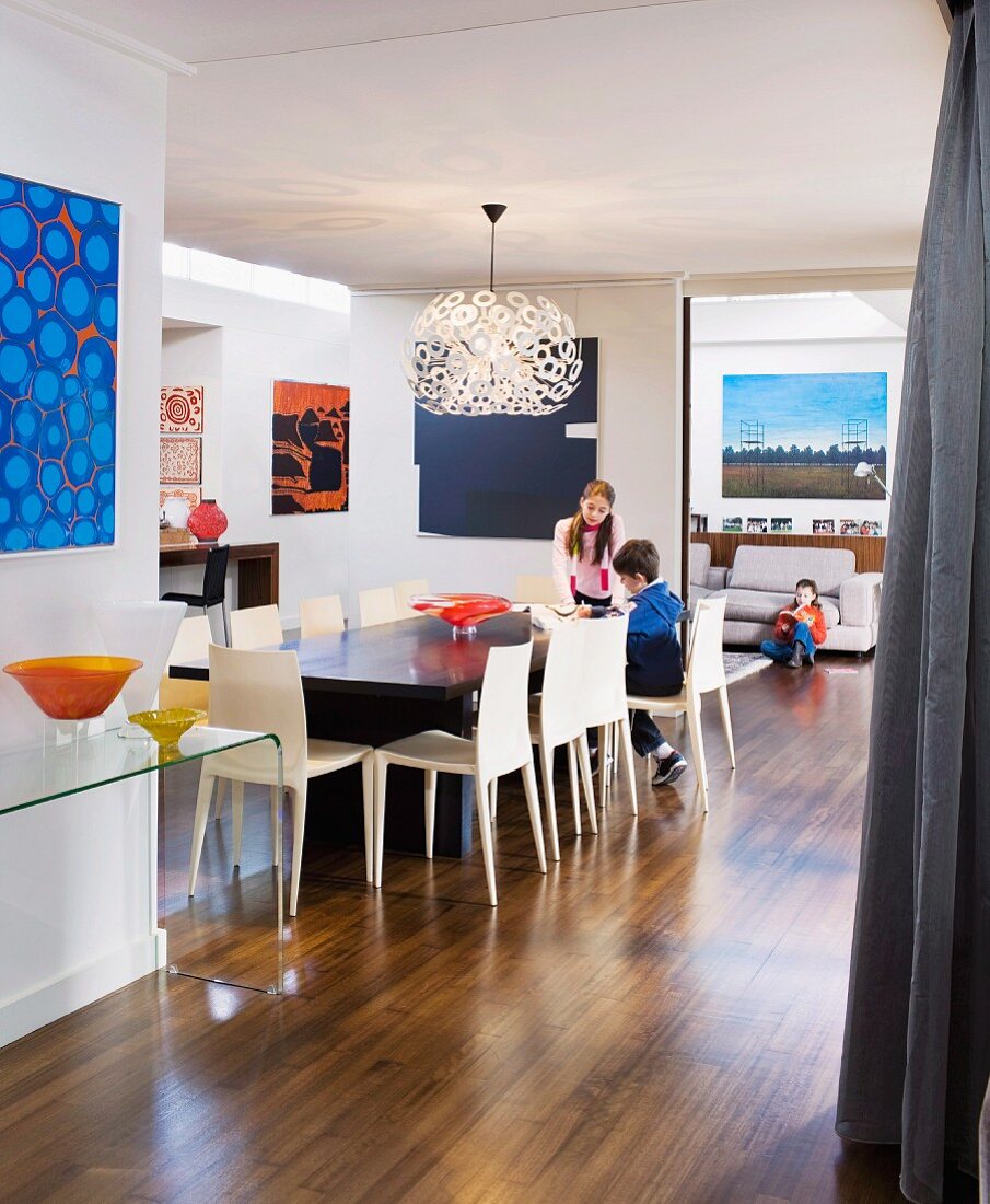 Collection of artworks and children in open-plan family room in contemporary interior decorated in 60s retro style