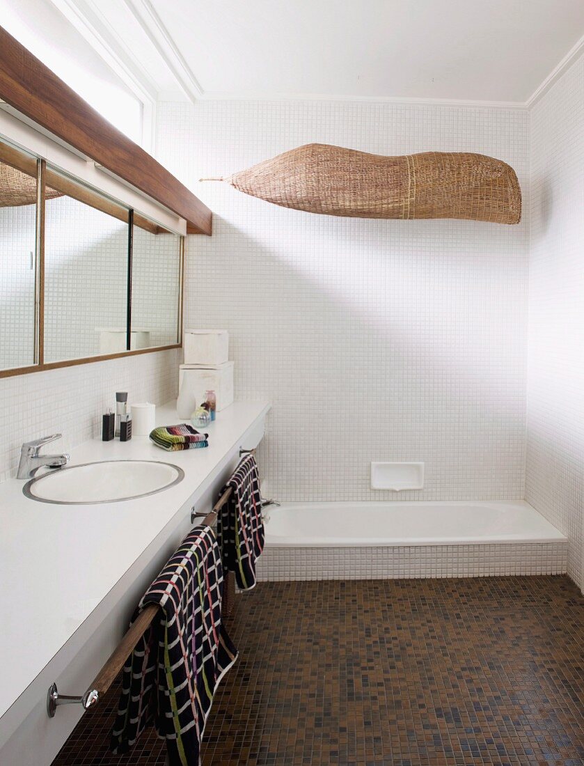 Braun changierendes Fliesenmosaik am Boden und weisses Mosaik an den Wänden eines modernen Designerbades mit durchgehender Waschtischablage