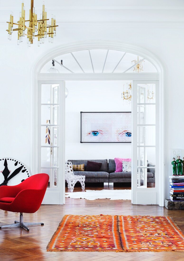 Mit verglasten Flügeltüren verbundene Altbauzimmer in der Wohnung eines Liebhabers von Kunst, zeitgenössischem Design und Retro Möbeln