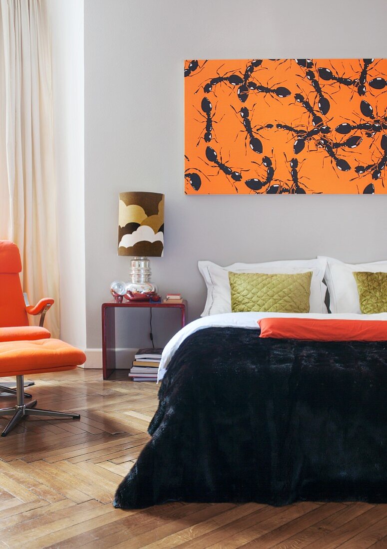 Contemporary screen print of ants above elegant double bed next to 70s retro lamp and armchair