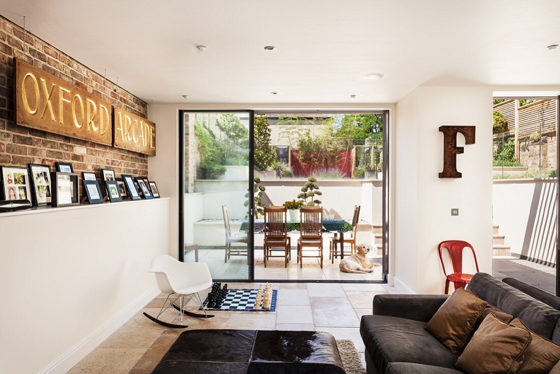 Englische Designerwohnung mit aufgestellter Fotogalerie und Sichtmauerwerk im Wohnbereich mit Terrassenblick