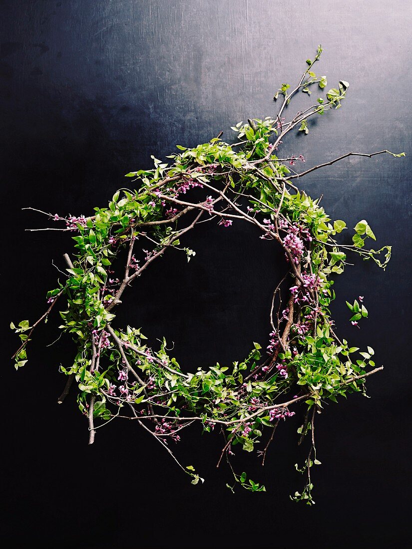 Hand-crafted wreath of twigs with leaves and purple flowers