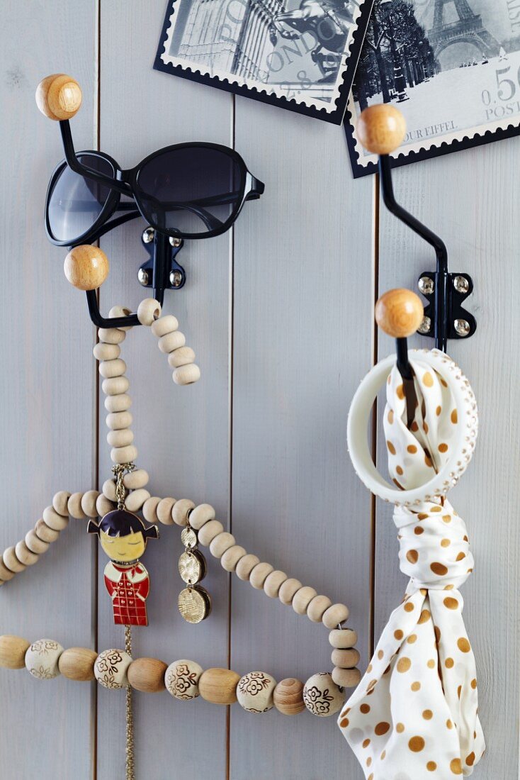 Metal wall hooks with round wooden ends on wooden wall and coathanger threaded with wooden beads