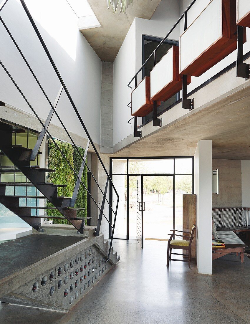 Puristische Stahltreppe und verglastes Türelement im Galerieflur eines zeitgenössischen Wohnhauses