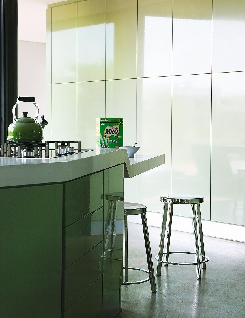 Island counter with lowered breakfast bar in designer kitchen with pastel green tip-on doors
