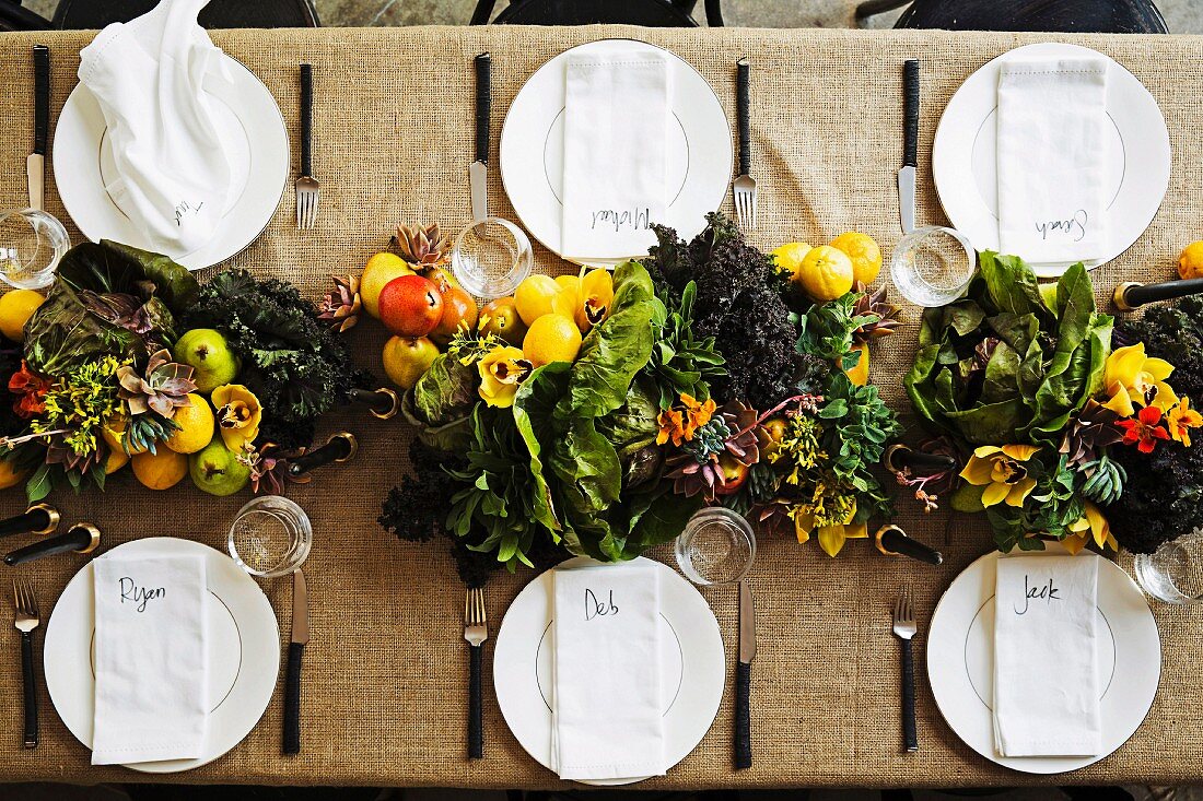 Gedeckter Tisch dekoriert mit Girlande aus Obst, Gemüse & Blüten
