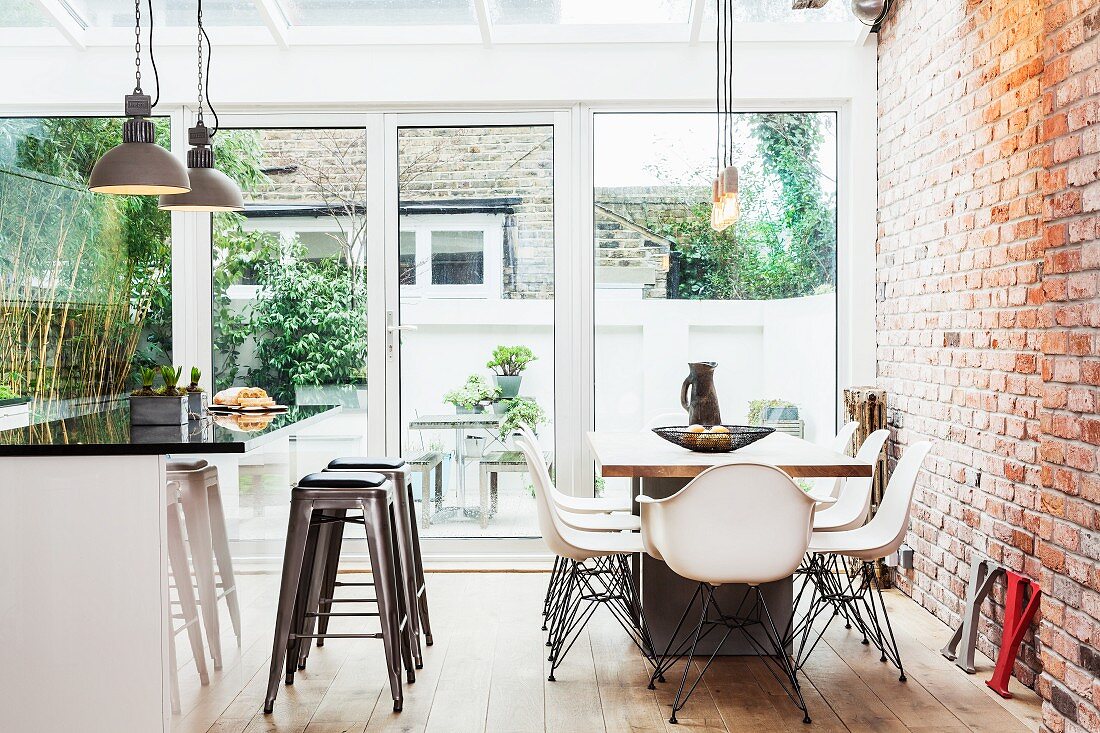 Modern dining area and island counter with bar stools in open-plan kitchen with exposed brickwork
