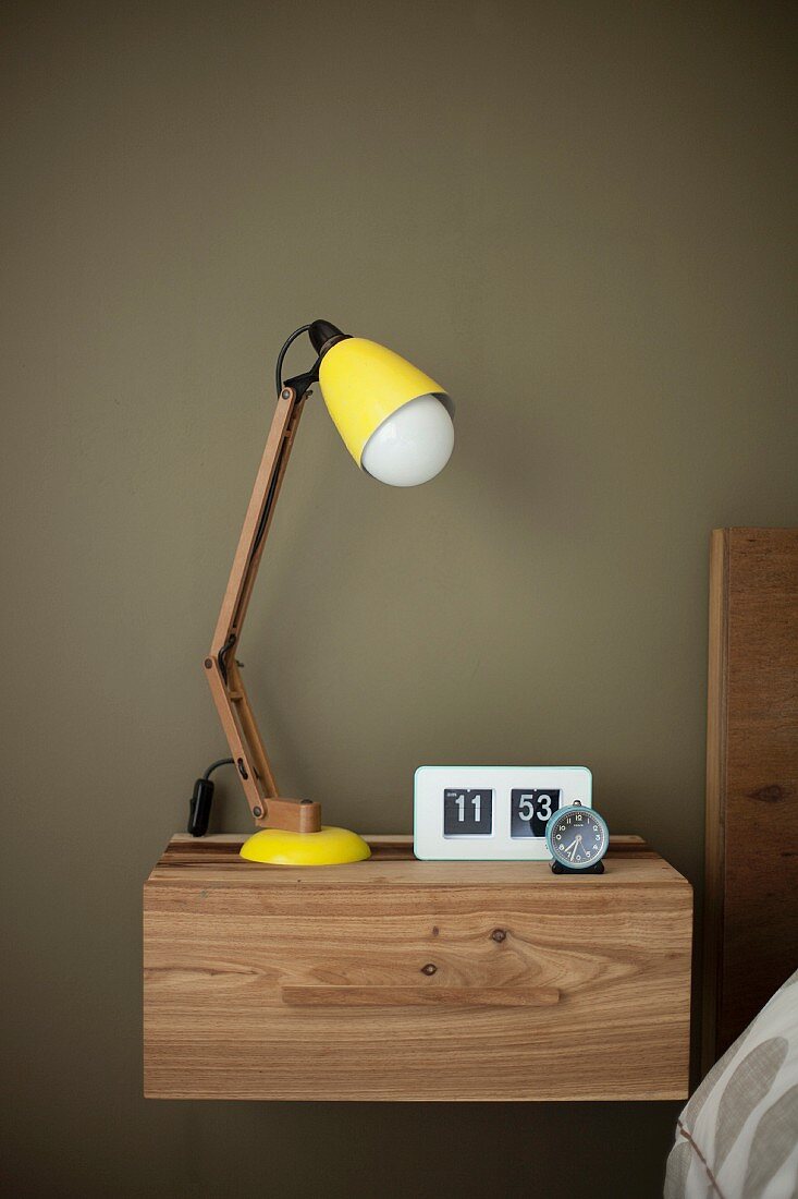 Retro, yellow table lamp on modern, wooden, wall-mounted bedside cabinet