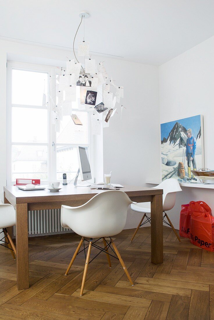 Schreibtisch mit Klassikerstühlen und Designer Zettel-Leuchte vor Fenster