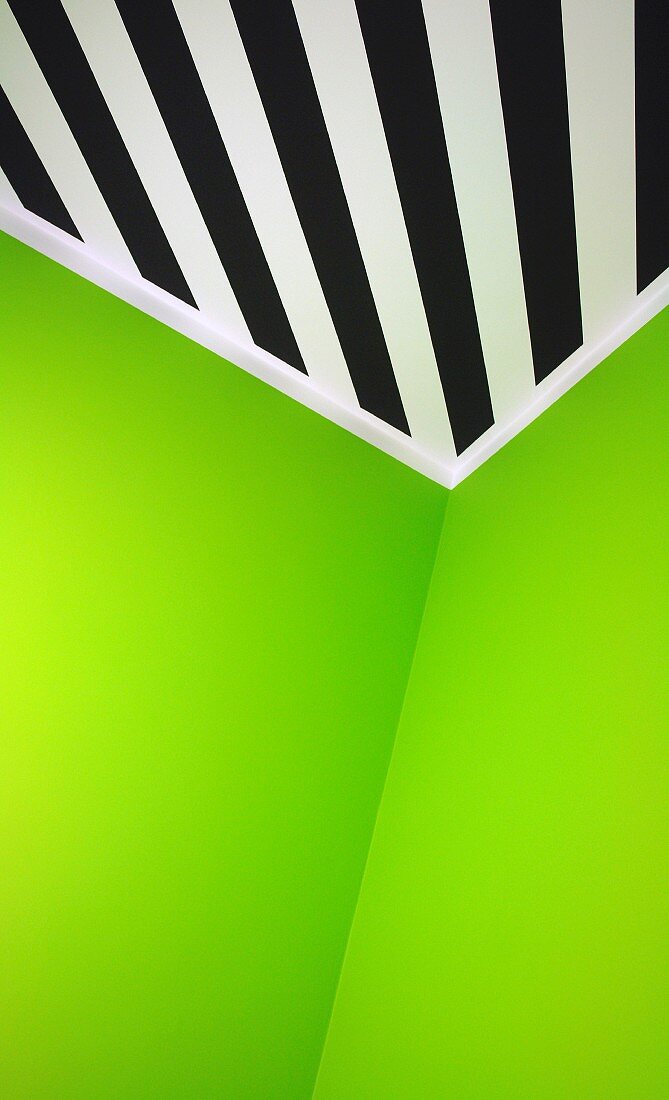 Grass green walls abutting ceiling painted with black and white diagonal stripes in corner