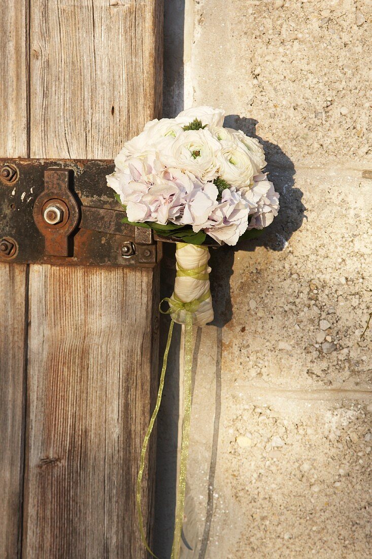 Posy of white flowers on vintage latch of wooden door