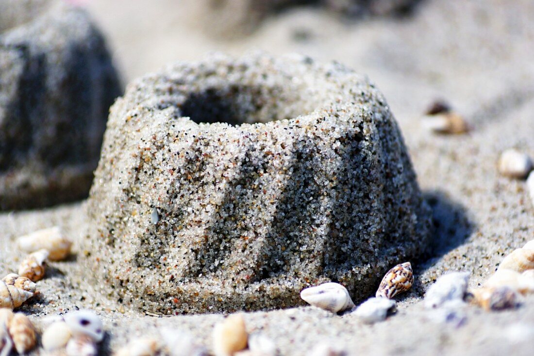 Gugelhupf aus Sand mit Muscheln am Strand