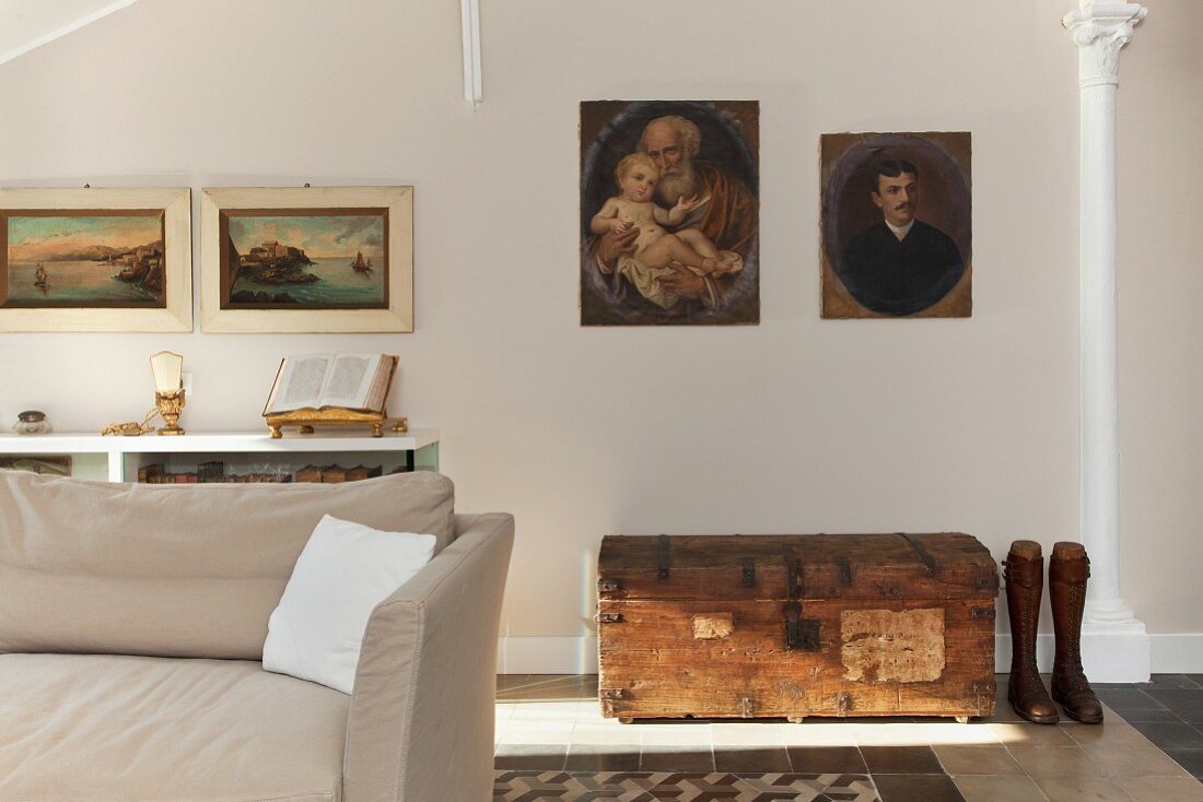 Italienische Gemäldesammlung an der Wand über einer Holztruhe im Wohnraum unterm Dach einer neoklassizistischen Villa in Ligurien