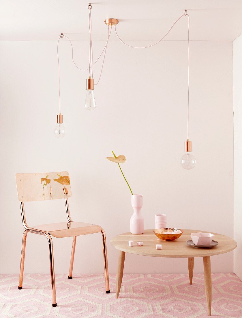 Coffeetable in hellem Holz, auf zartrosa Teppichmuster, ergänzt durch den weichem Kupferschimmer von Stuhl und Hängelampen