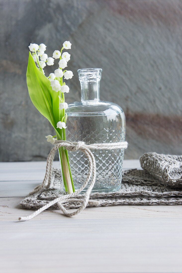 Lily of the valley tied to vintage glass bottle with cord