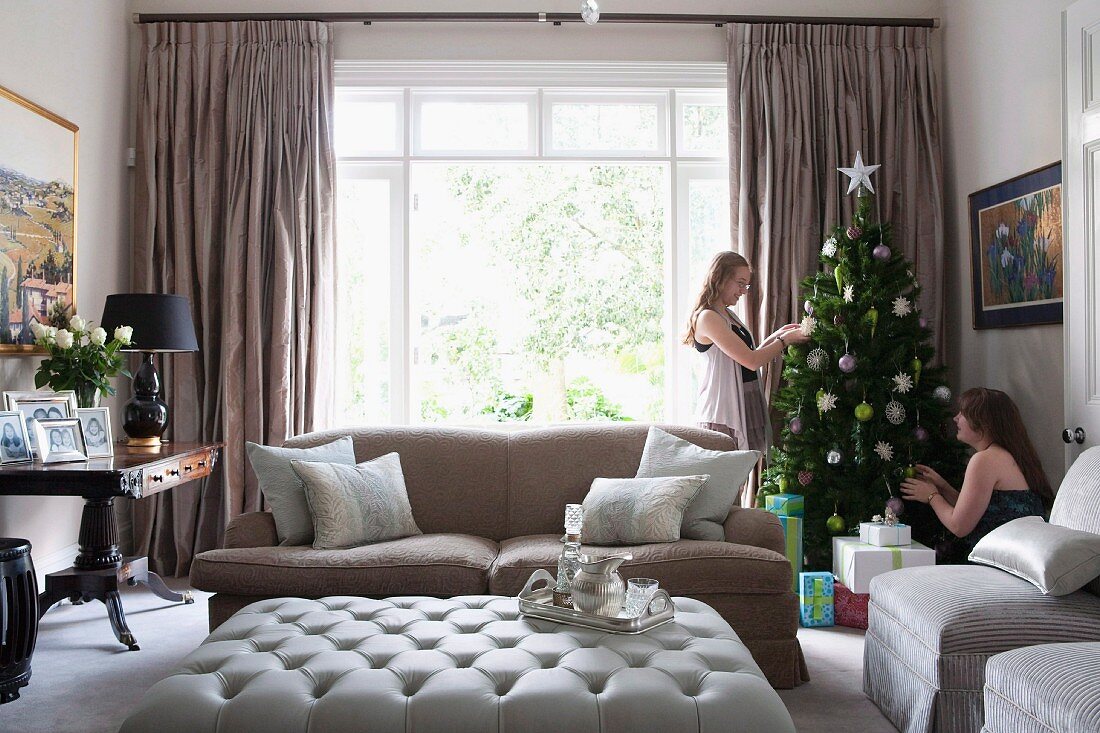 Zwei Mädchen beim Schmücken des Weihnachtsbaumes in elegantem Wohnzimmer