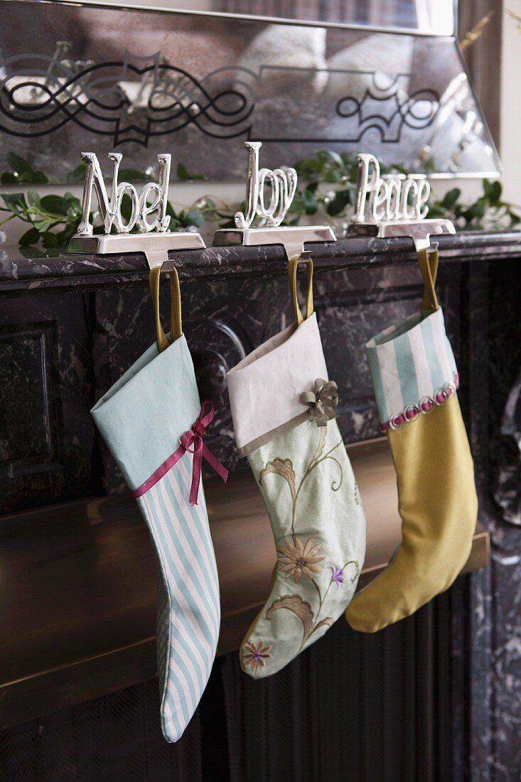 Christmas stocking hung from motto ornaments with hook on marble mantelpiece