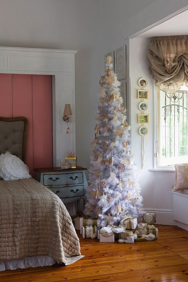 Weissgoldener, romantischer Weihnachtsbaum mit Geschenkpäckchen in antikisierendem Mädchenzimmer