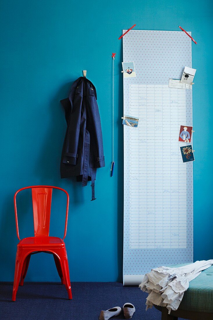 Tapetenrolle mit Masking Tapes an blaue Wand geklebt, verschiedene Postkarten sind mit Klammern daran befestigt