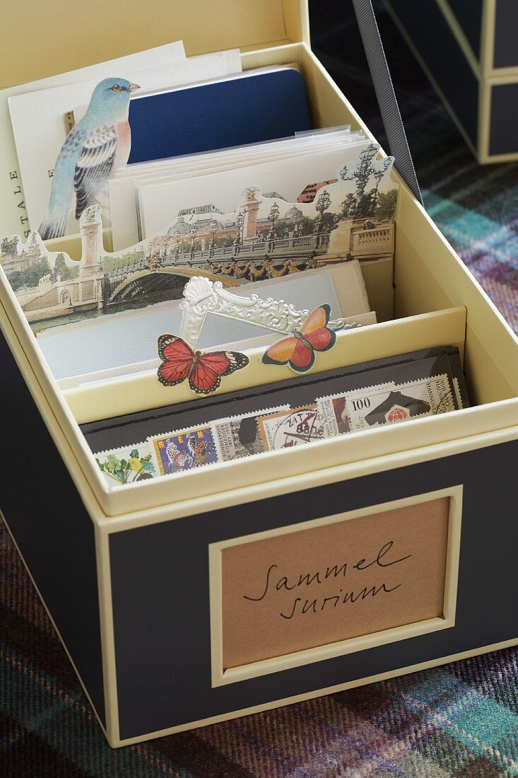 Elegante Pappschachtel mit verschiedenen Briefmarken und Postkarten