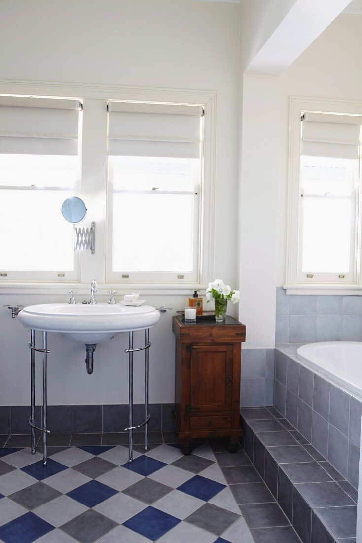 Bathroom with vintage washstand, diagonal chequered floor and bathtub on platform