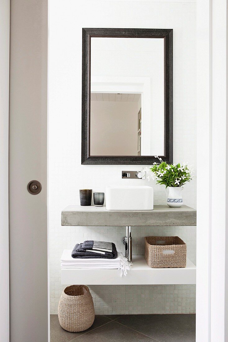 Blick durch offene Schiebetür auf modernen Waschtisch und gerahmtem Spiegel