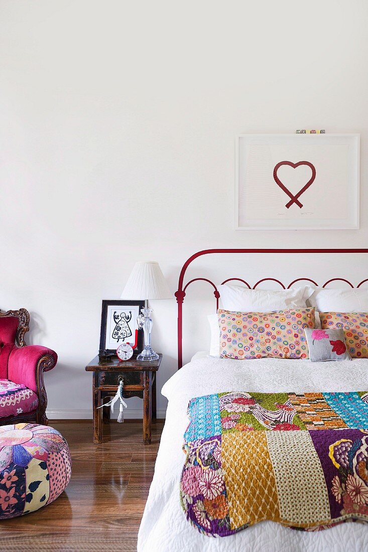 Picture of heart above red metal bed with patchwork blanket