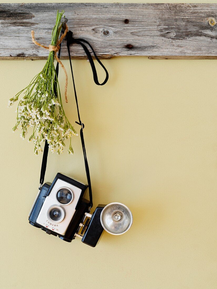 Antique camera and posy hanging from wooden peg board